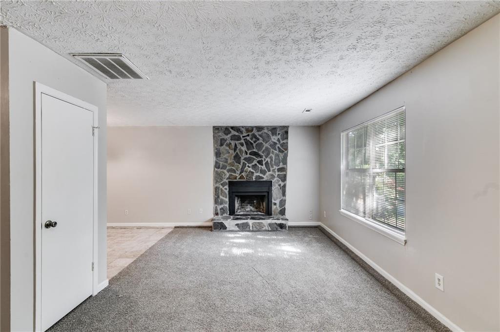 a view of an empty room with a fireplace and a window