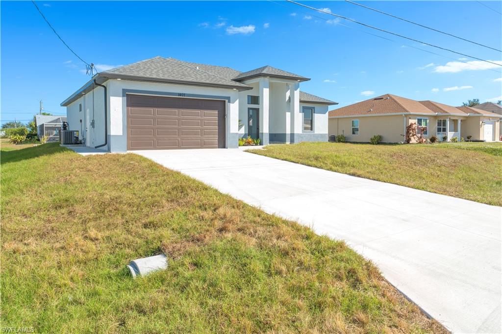 View of front of house featuring central AC, a front yard, and a garage