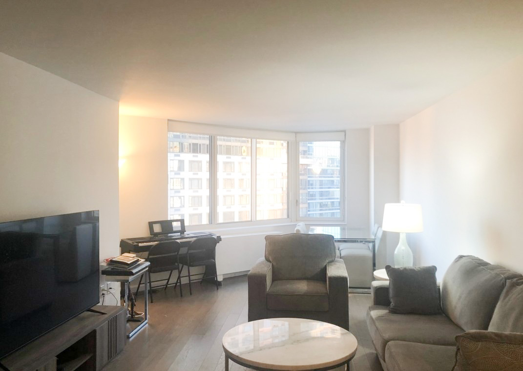 a living room with furniture a large window and a flat screen tv