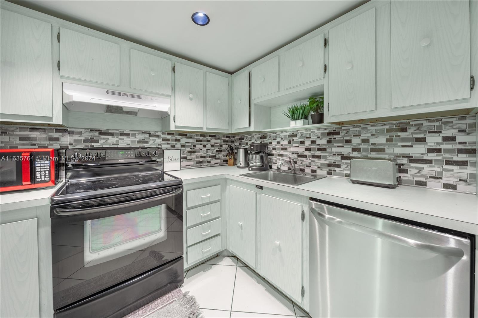 a kitchen with white cabinets and appliances