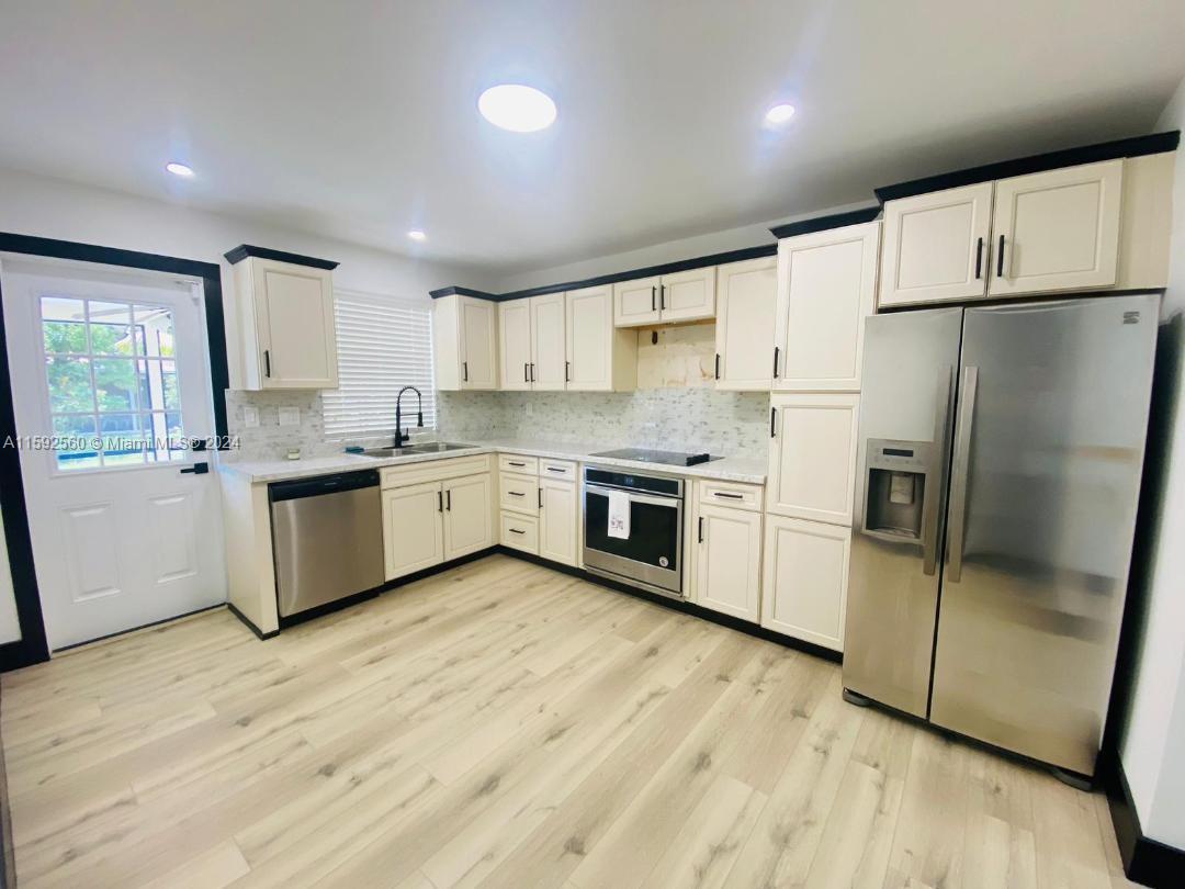 a kitchen with stainless steel appliances a refrigerator a sink and white cabinets