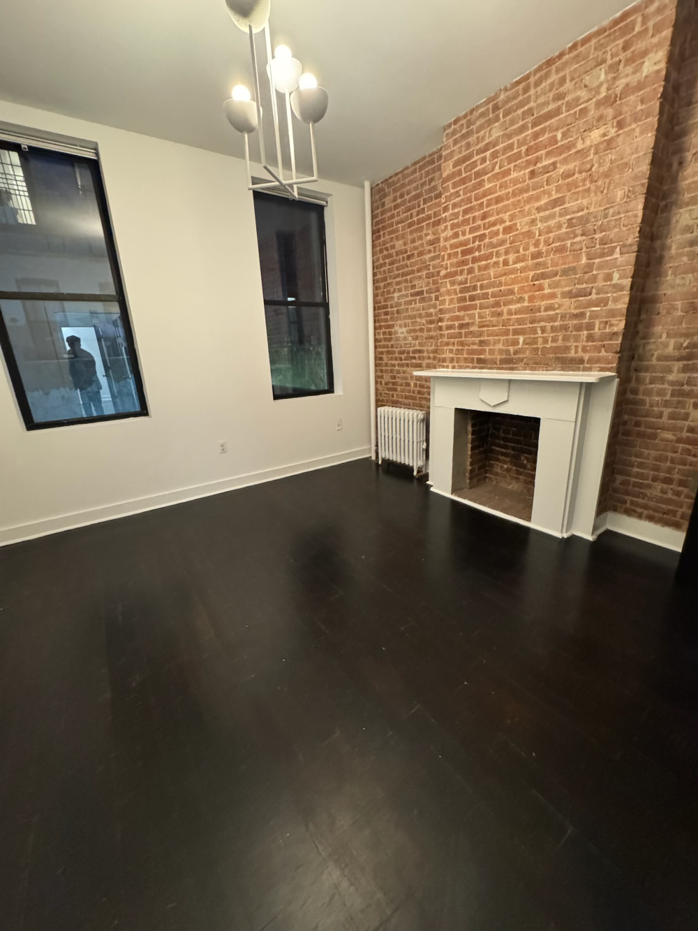 an empty room with wooden floor fireplace and windows