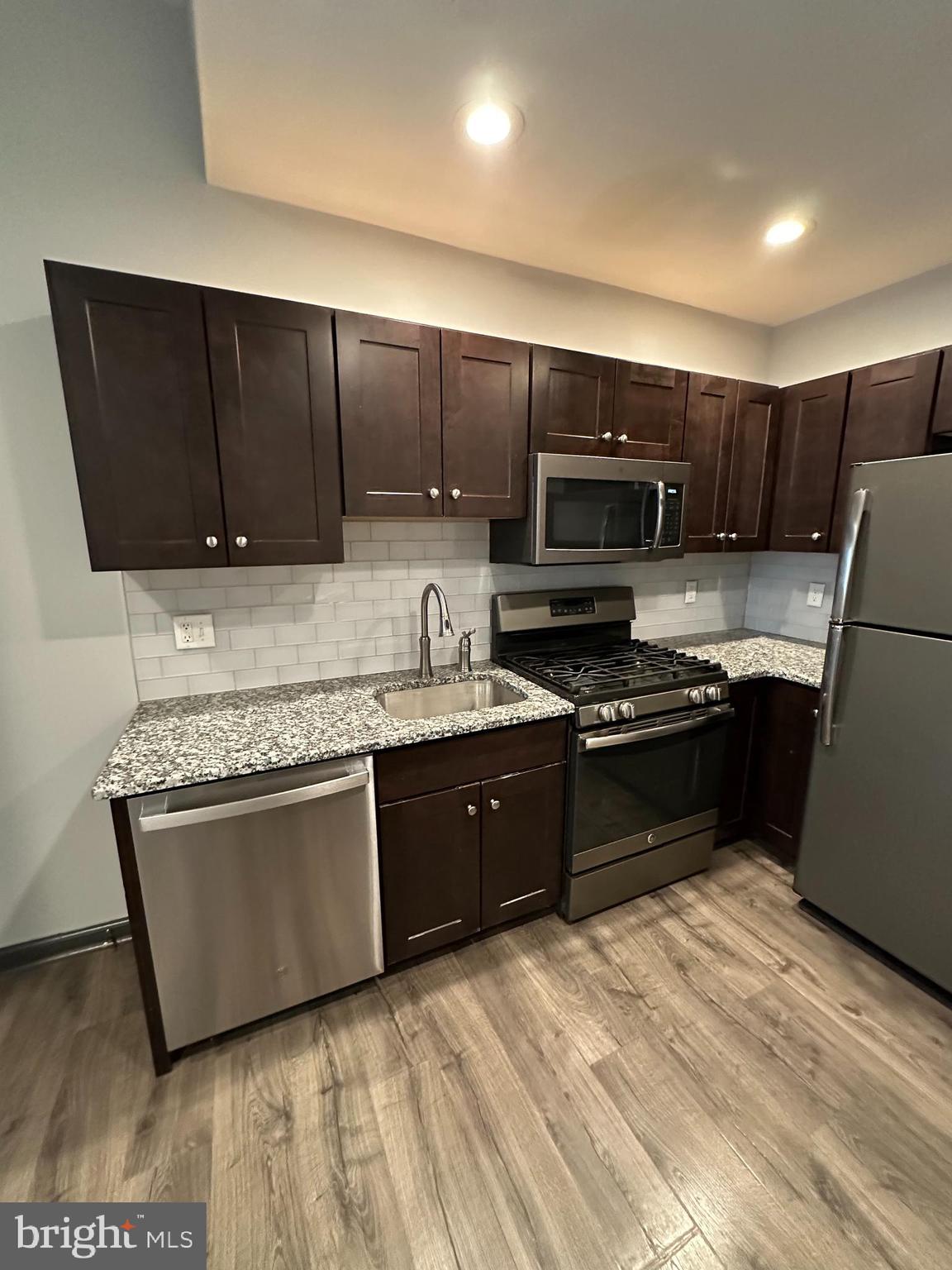 a kitchen with stainless steel appliances granite countertop a stove a sink and a microwave