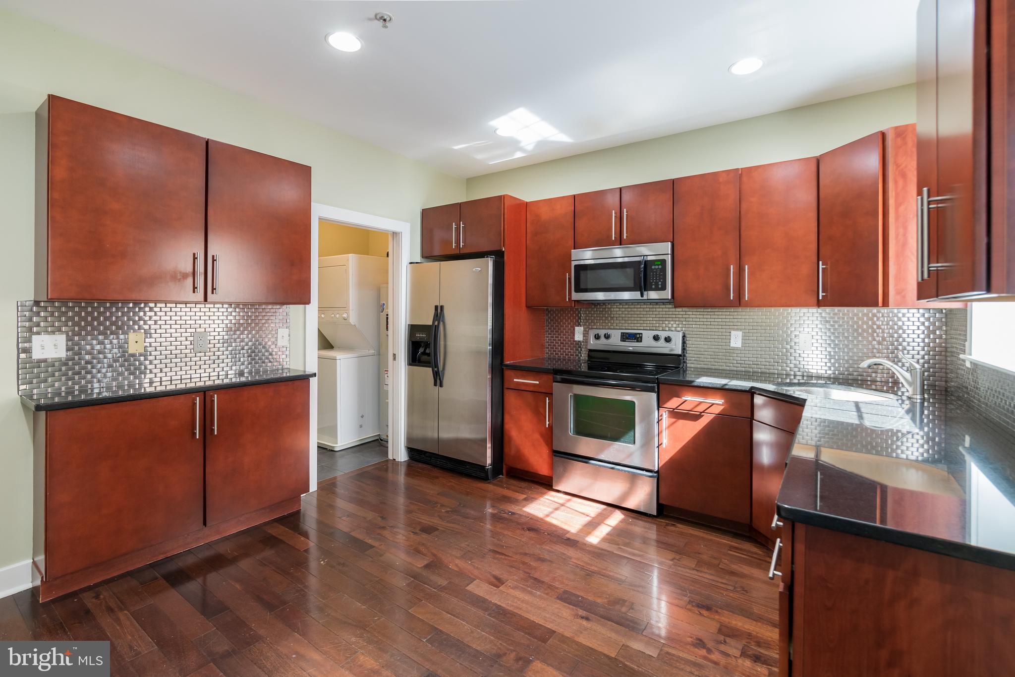 a kitchen with stainless steel appliances granite countertop wooden cabinets a stove a sink and a center island