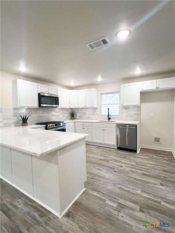 a large kitchen with stainless steel appliances granite countertop a stove a sink and a microwave