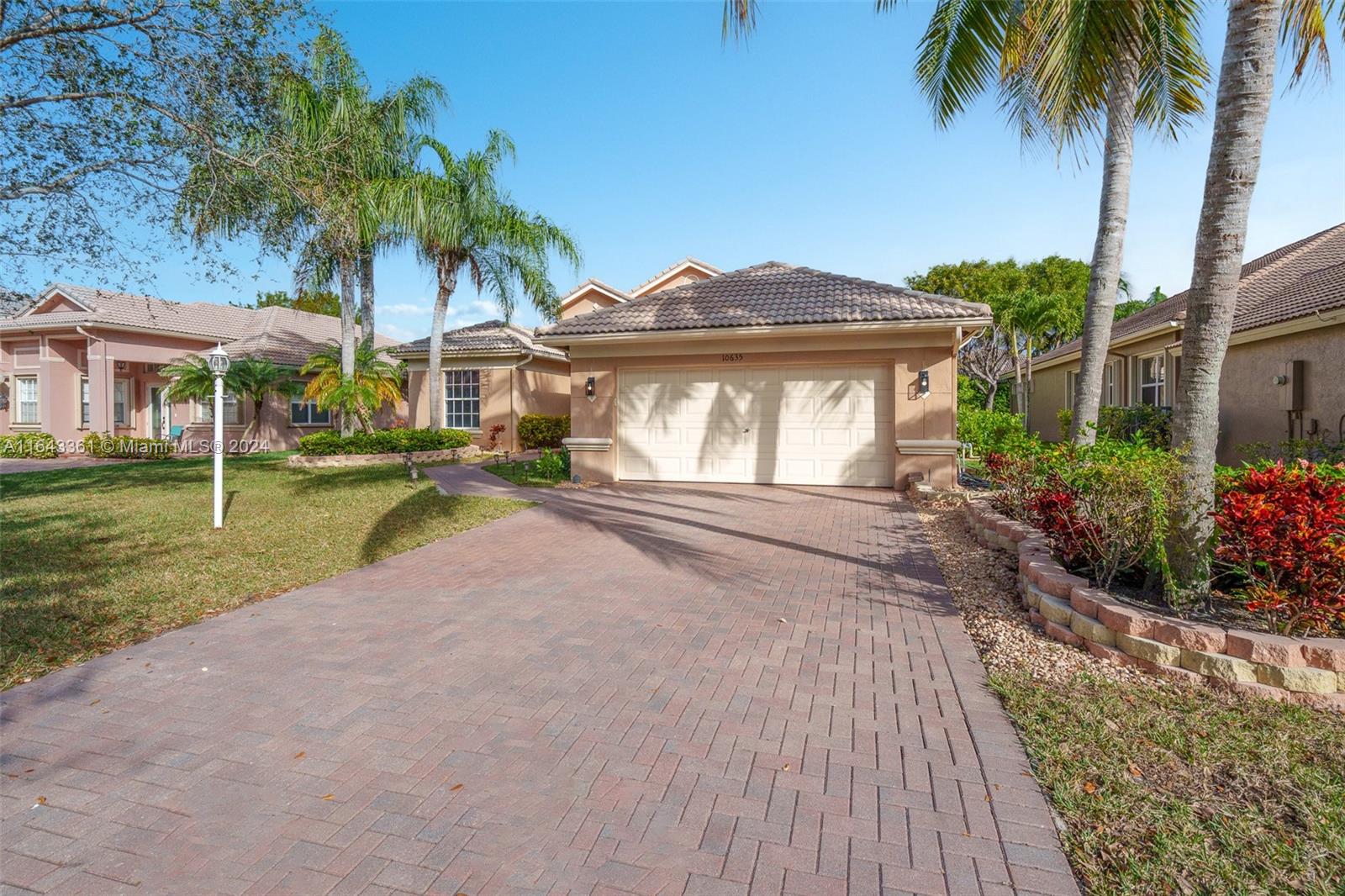 a front view of a house with a garden and palm trees