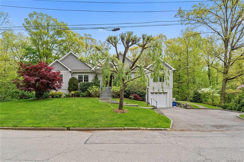 a front view of a house with a garden and trees