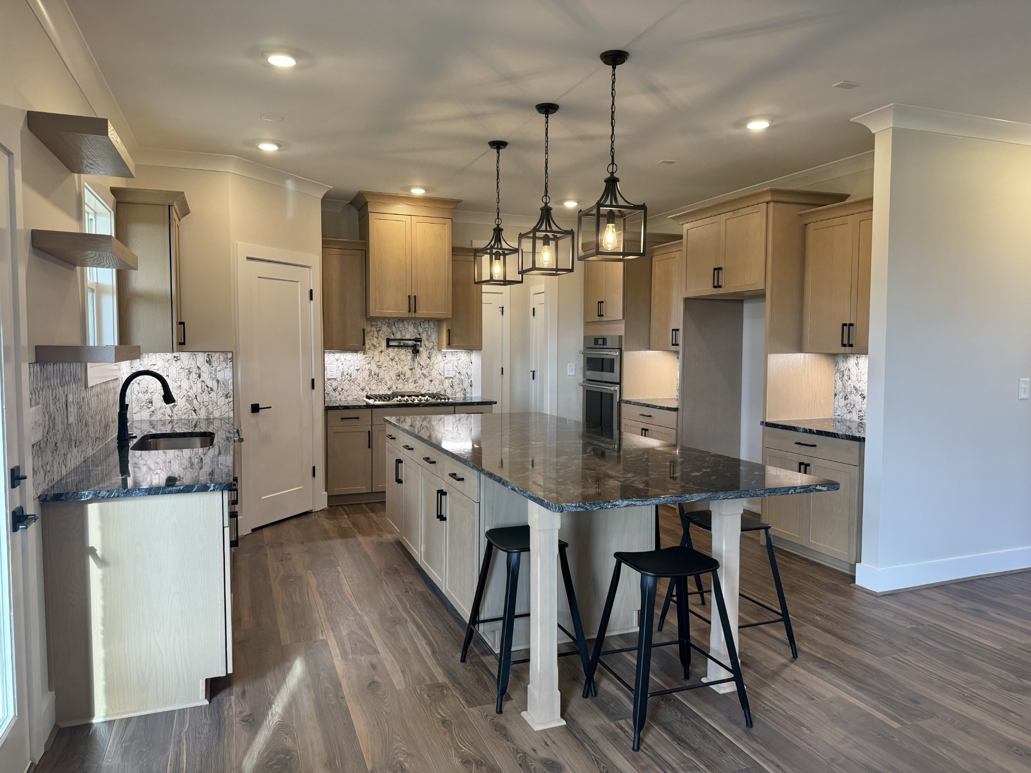 a kitchen with stainless steel appliances kitchen island granite countertop a dining table chairs and white cabinets