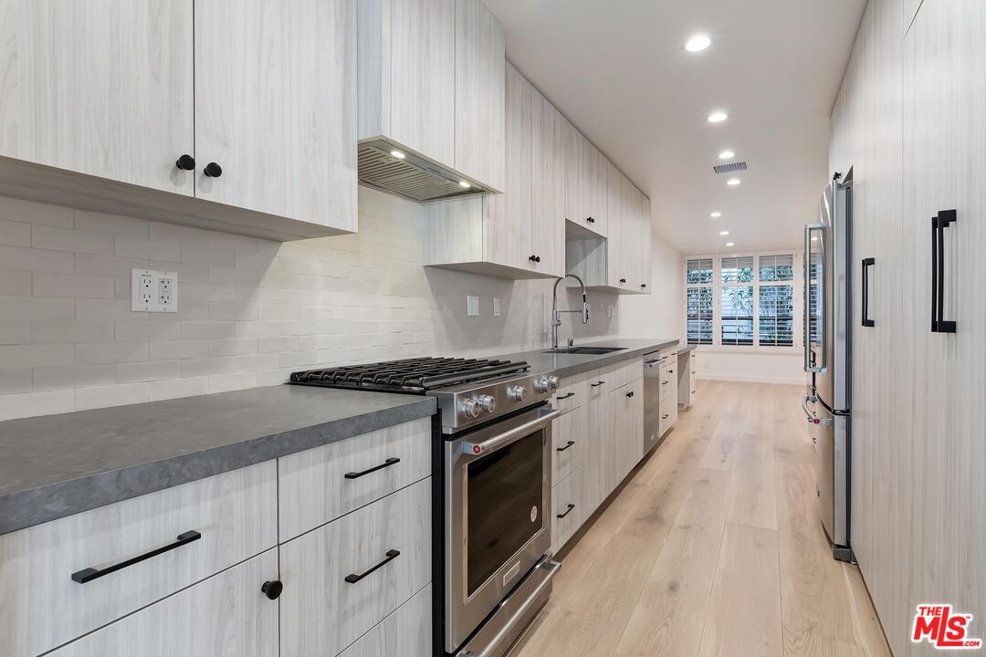 a kitchen with stainless steel appliances granite countertop a stove a sink and a refrigerator