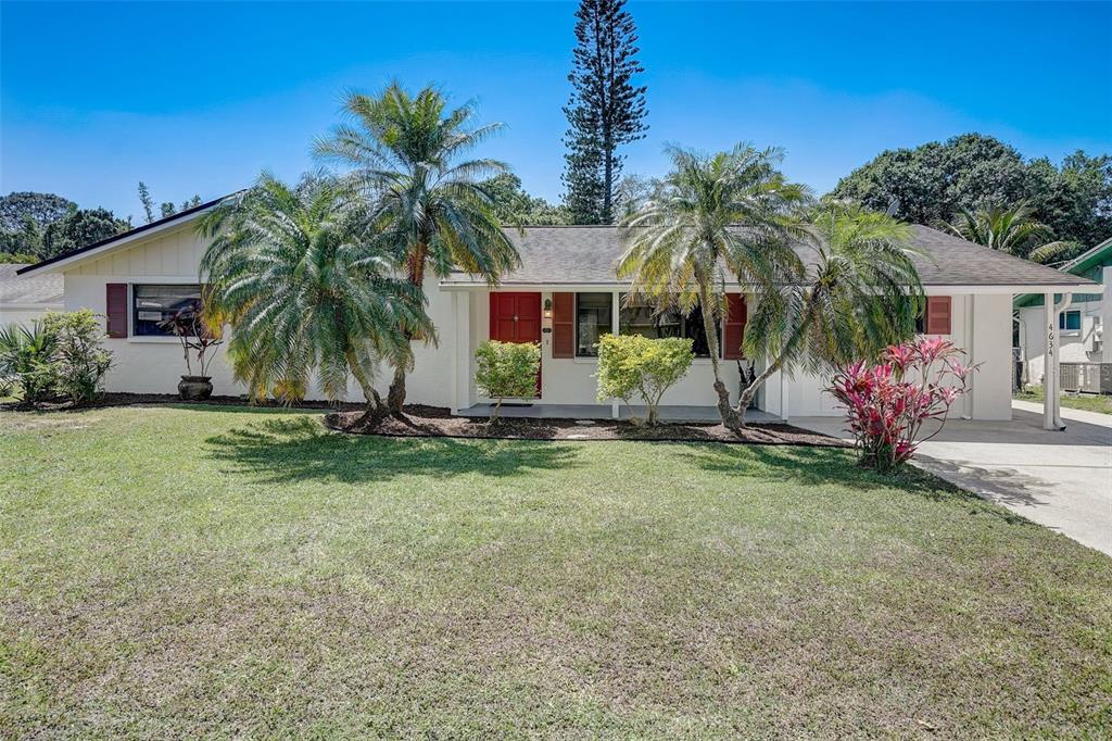 a view of a house with a yard and palm trees