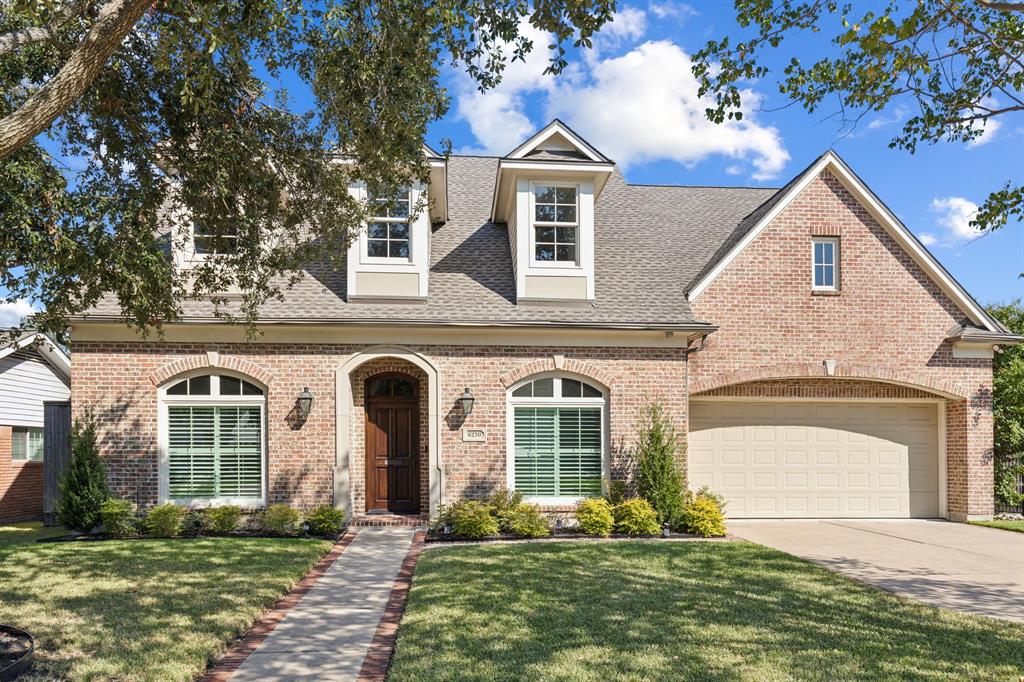 Welcome to 6230 Locke Lane, a beautiful brick home with great curb appeal.  The lush landscaping and manicured lawn create a welcoming atmosphere. The pathway, lined with brick accents, seamlessly guides you to the front entry, emphasizing the home’s thoughtful design and inviting nature.