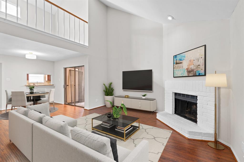 Step into this inviting living area, where elegance and warmth embrace you. The high ceiling and open layout create an airy atmosphere, while the hardwood flooring and fireplace add a touch of coziness (virtual stage)