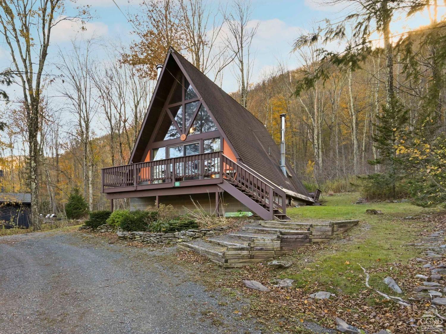 a view of wooden house with a small yard and a large tree