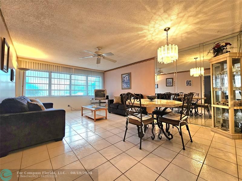 a living room with furniture a large window and kitchen view