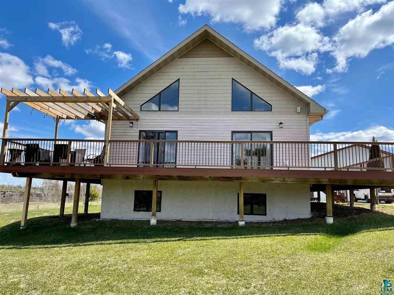 Rear view of house featuring a lawn, a pergola, and a deck