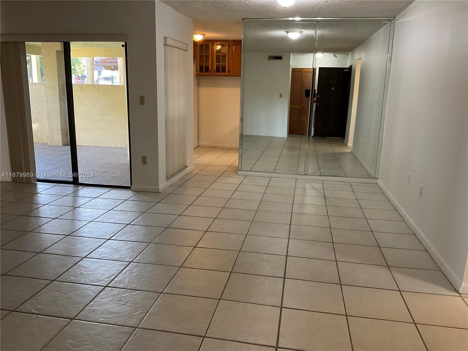 a view of a hallway and an empty room with a mirror