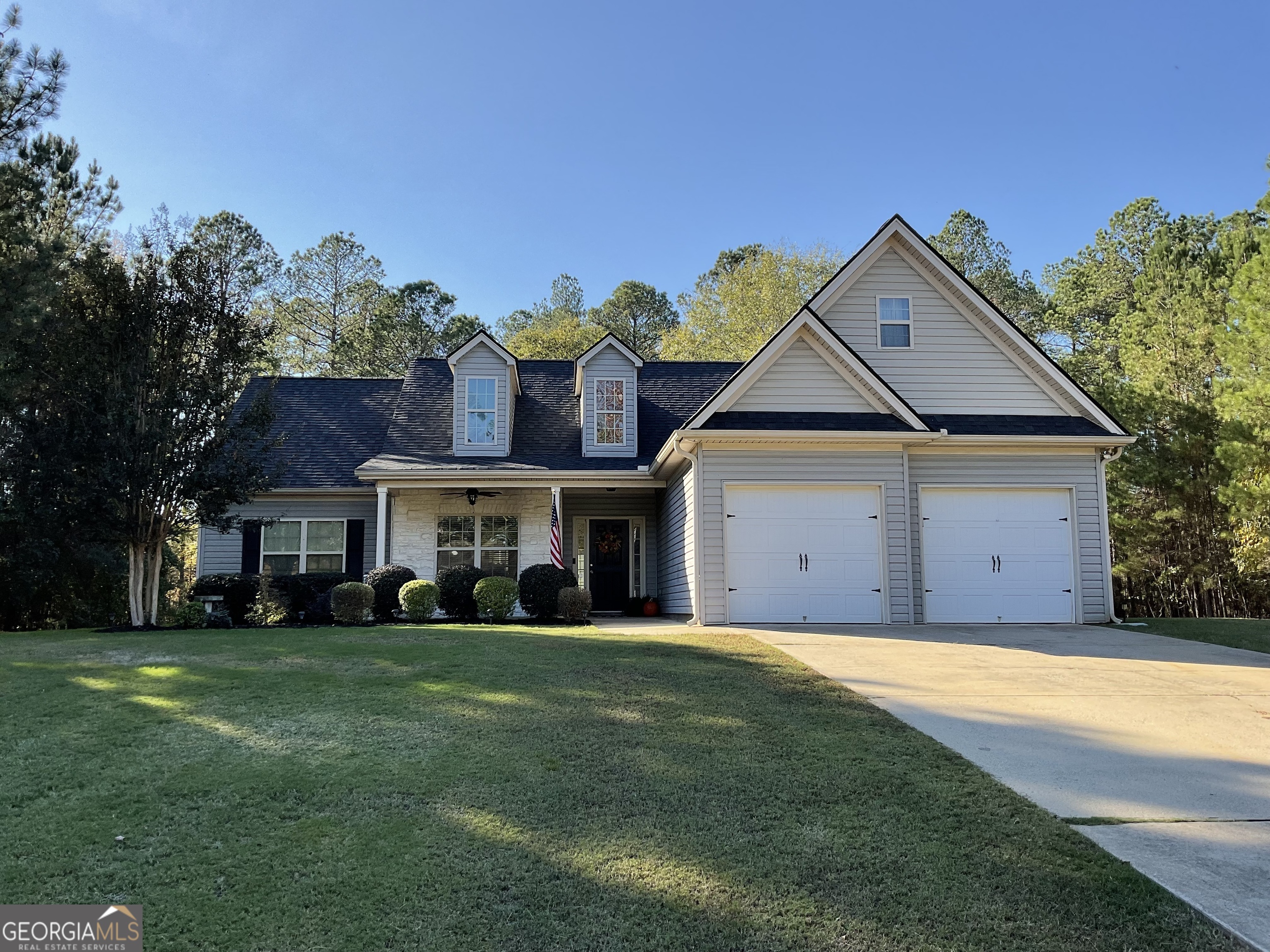 a front view of a house with a garden and trees