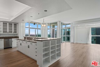 a large white kitchen with granite countertop a large window and cabinets