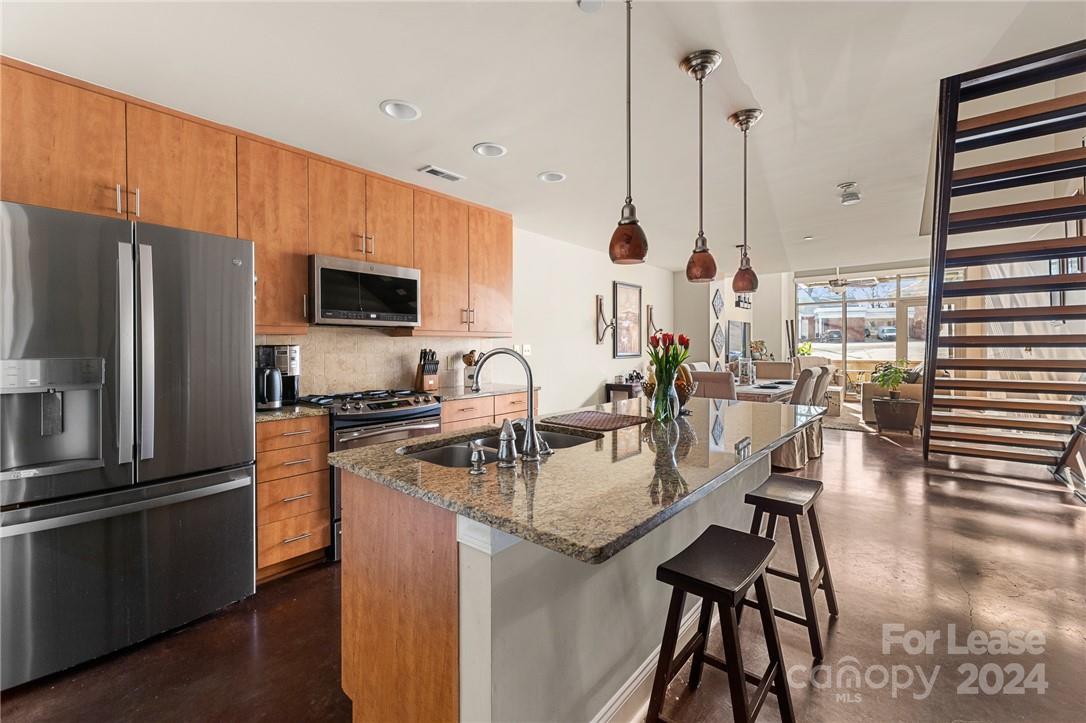 a kitchen with stainless steel appliances granite countertop a stove top oven a sink a dining table and chairs