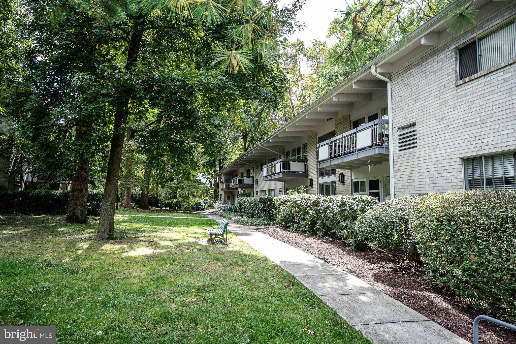 a view of house in front of a big yard with large trees