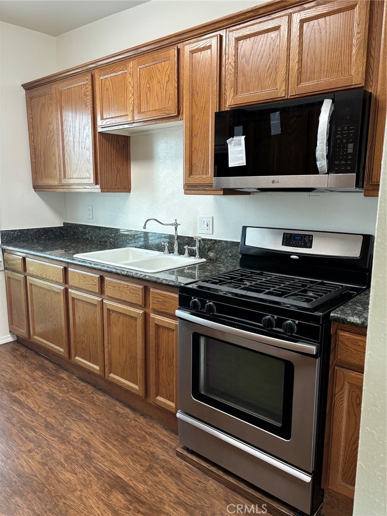 a kitchen with granite countertop a stove microwave and sink