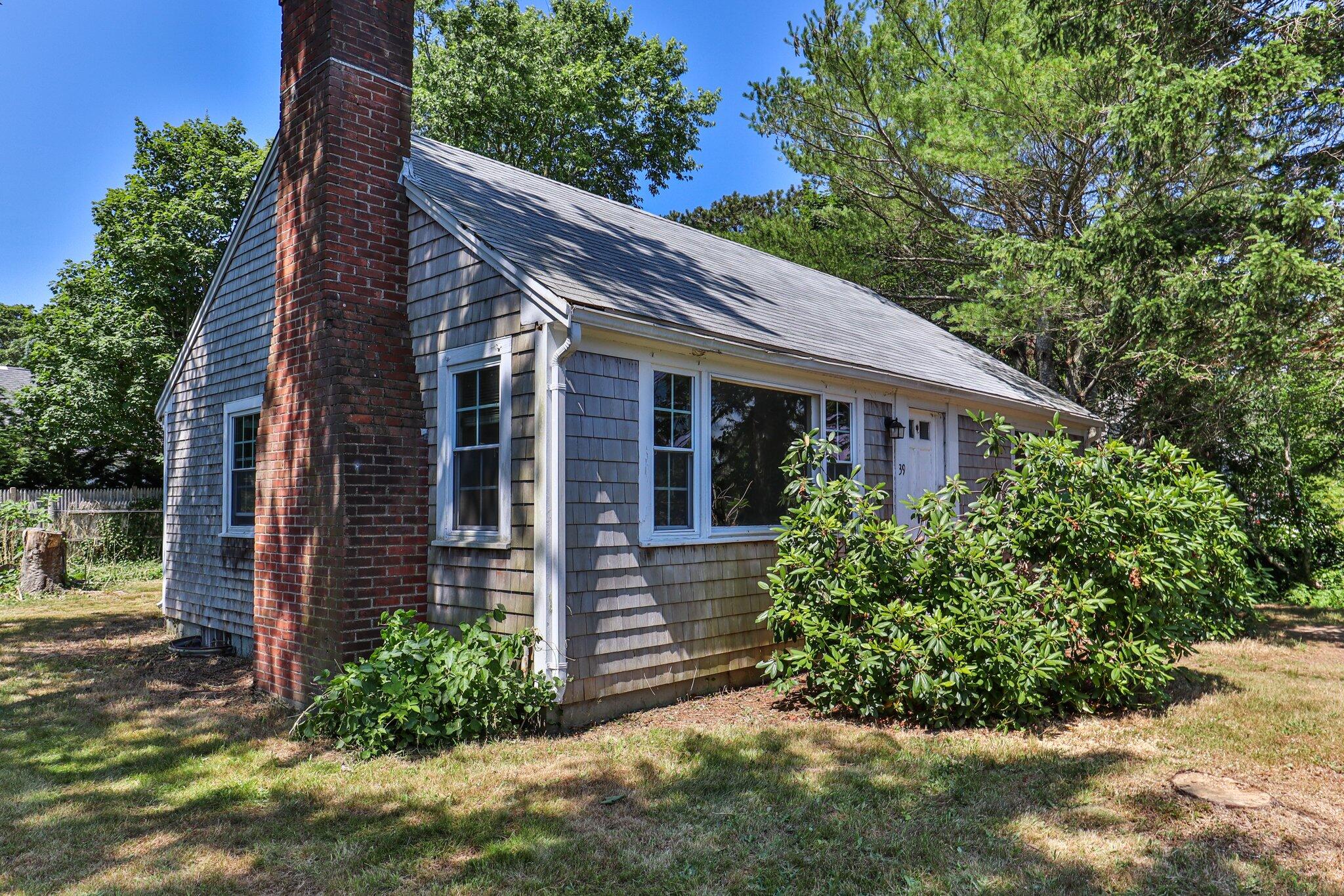 a view of a house with brick walls plants and large tree