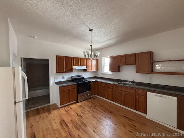 a kitchen with granite countertop a refrigerator stove top oven and sink