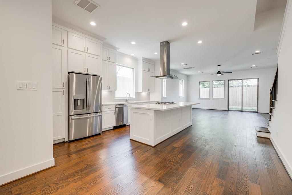 a kitchen with stainless steel appliances wooden floor and window