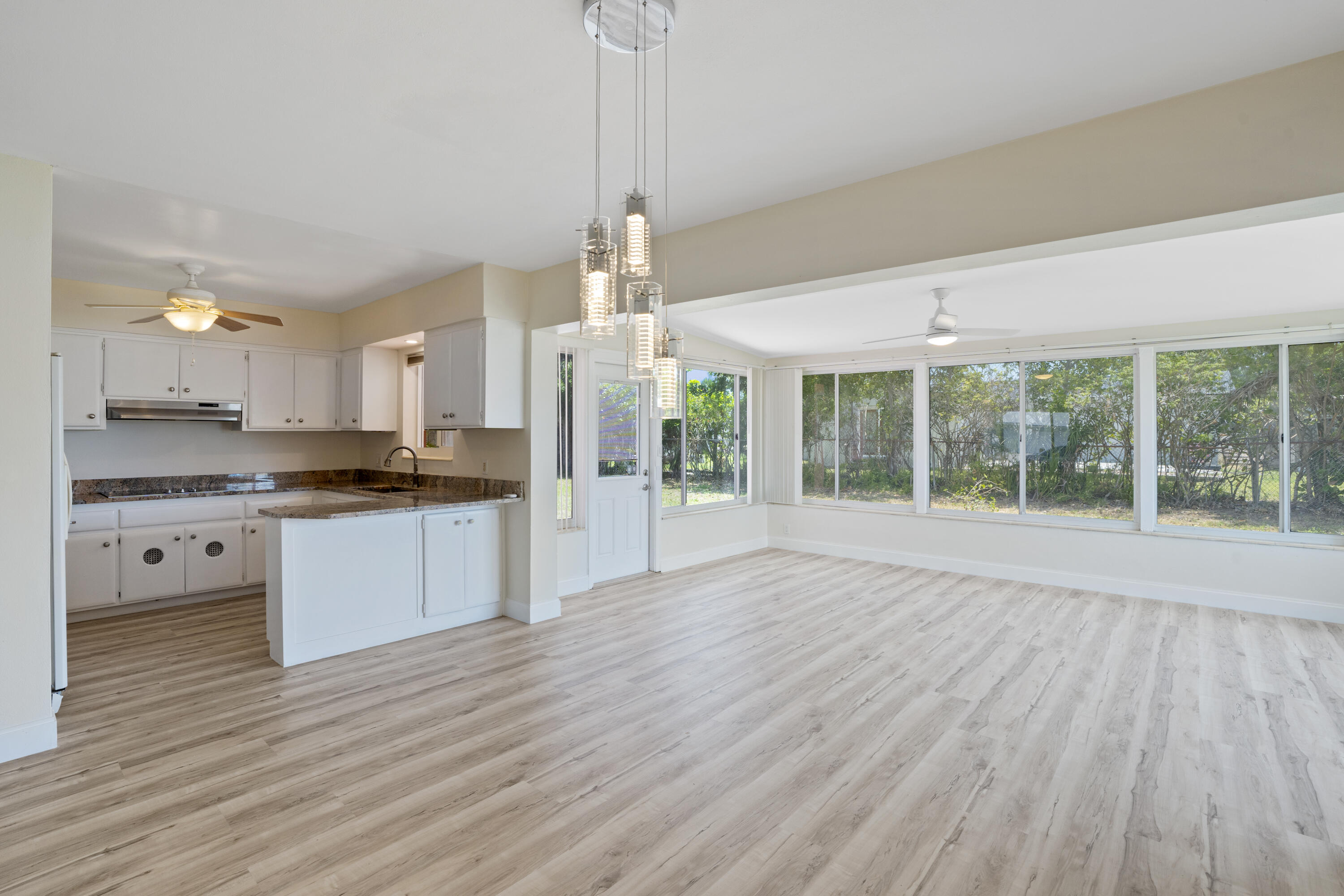 a large kitchen with white cabinets and wooden floor