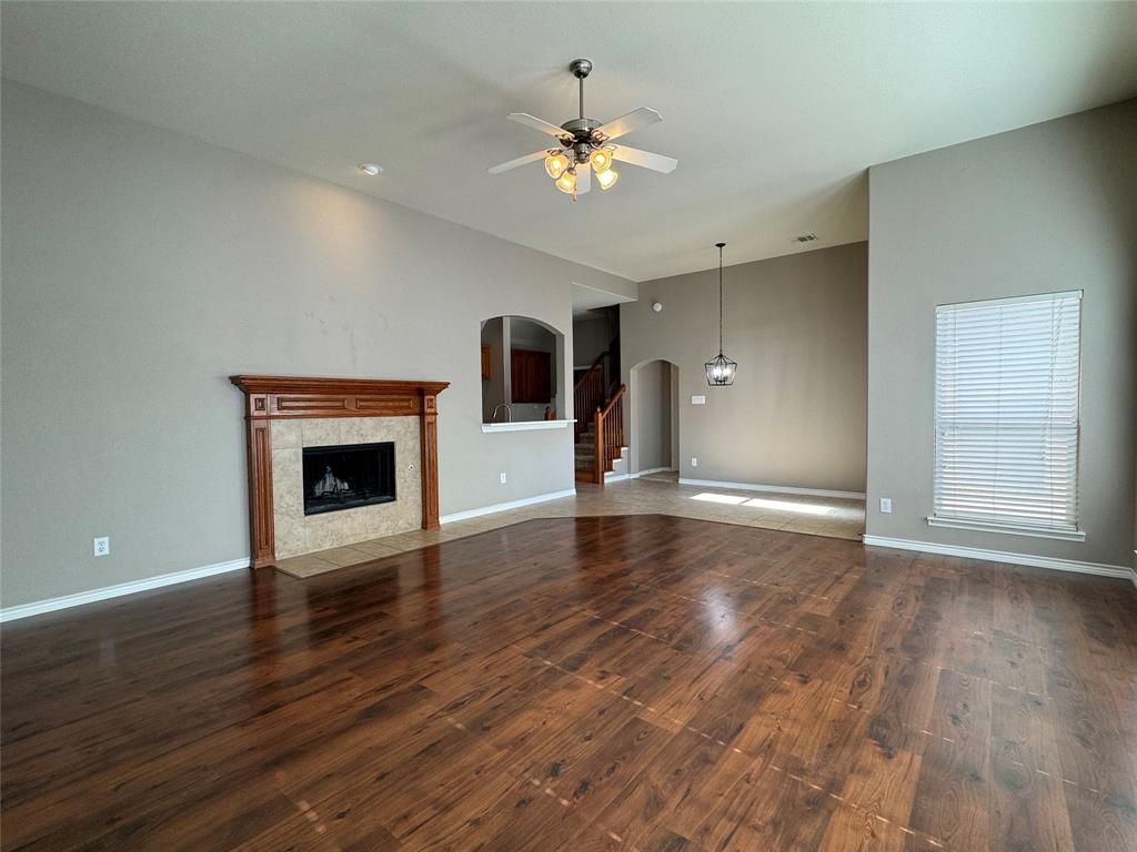 a view of an empty room with wooden floor and a fireplace