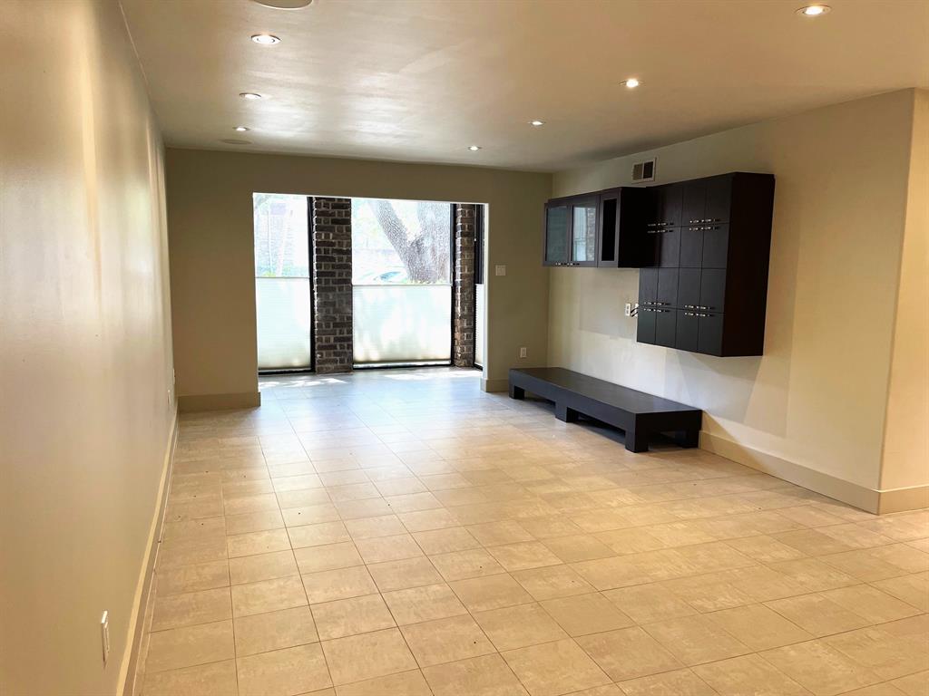 a view of an empty room with wooden floor and a kitchen