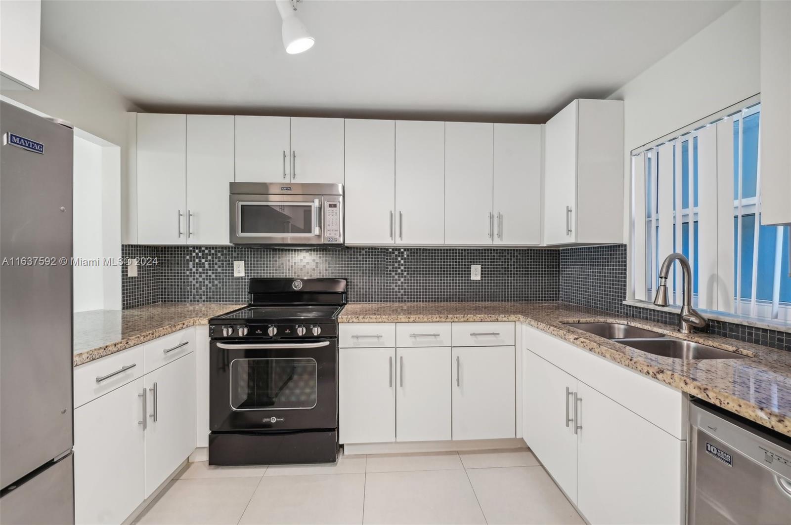 a kitchen with granite countertop white cabinets and stainless steel appliances