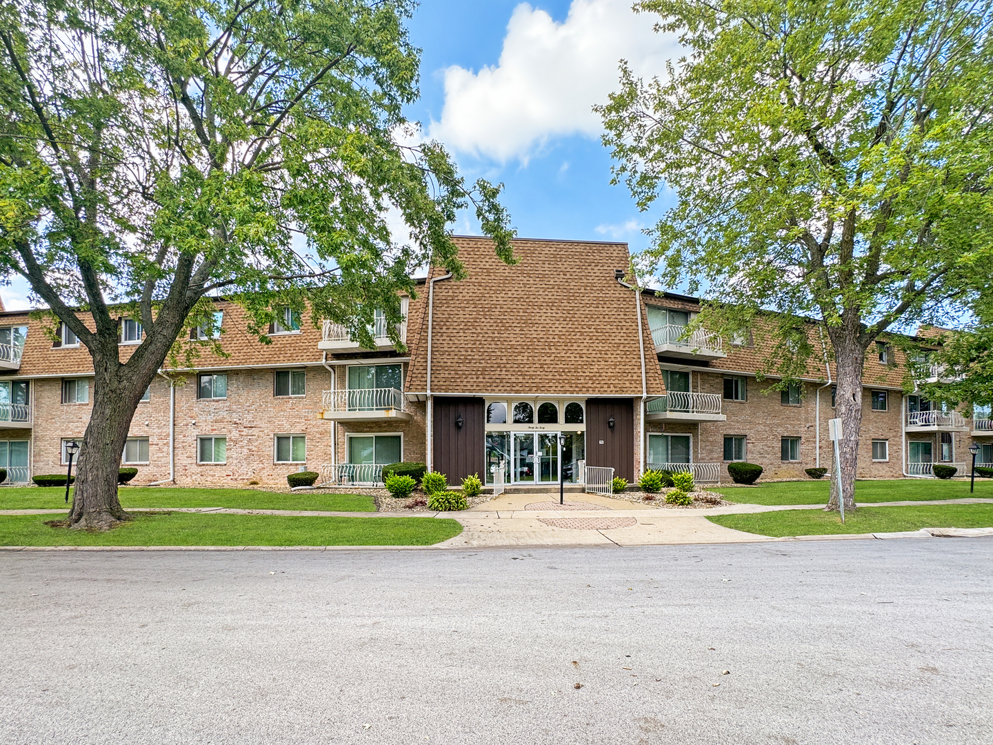 a front view of a building with a garden and trees