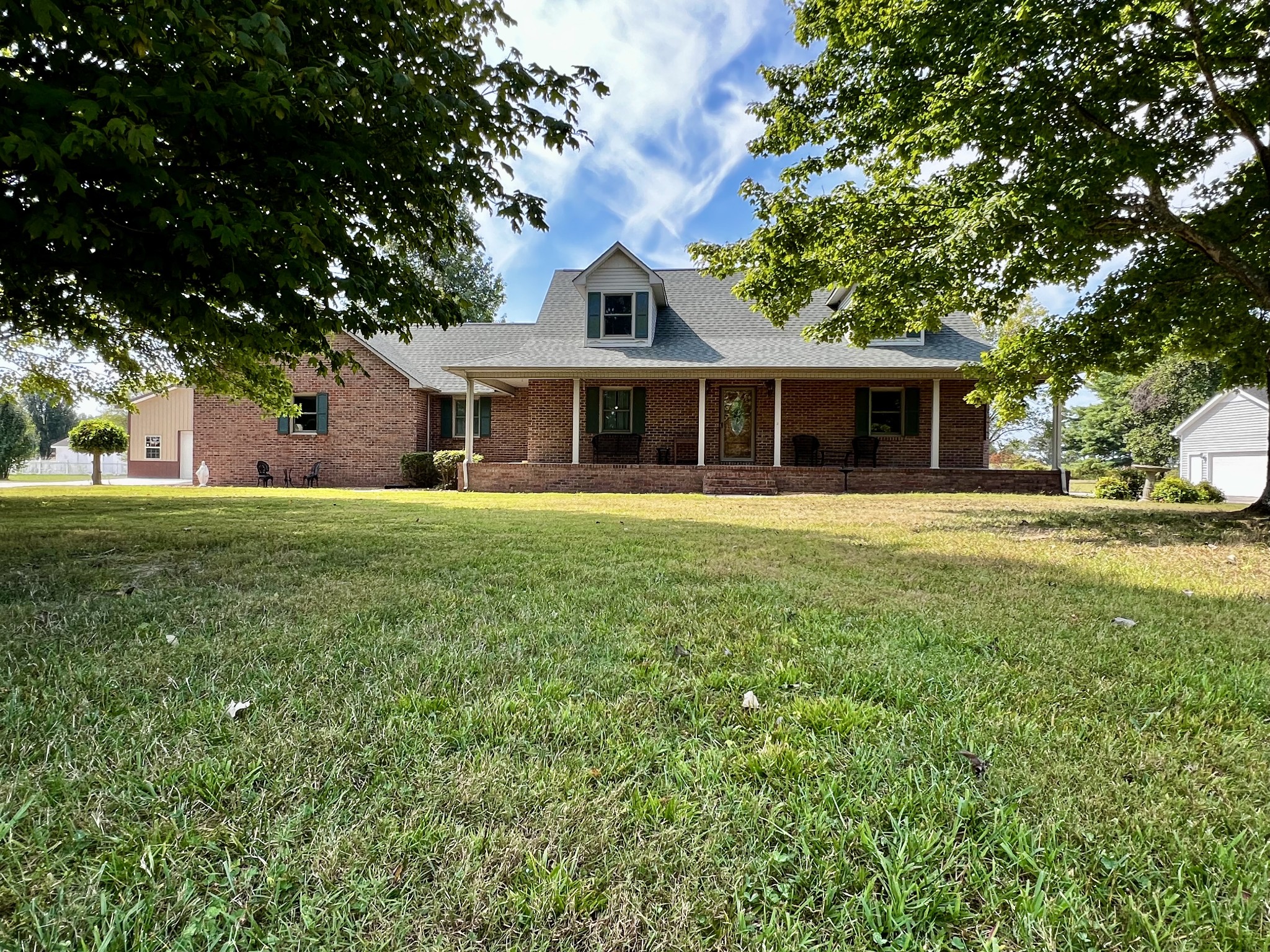 a front view of a house with a garden and trees