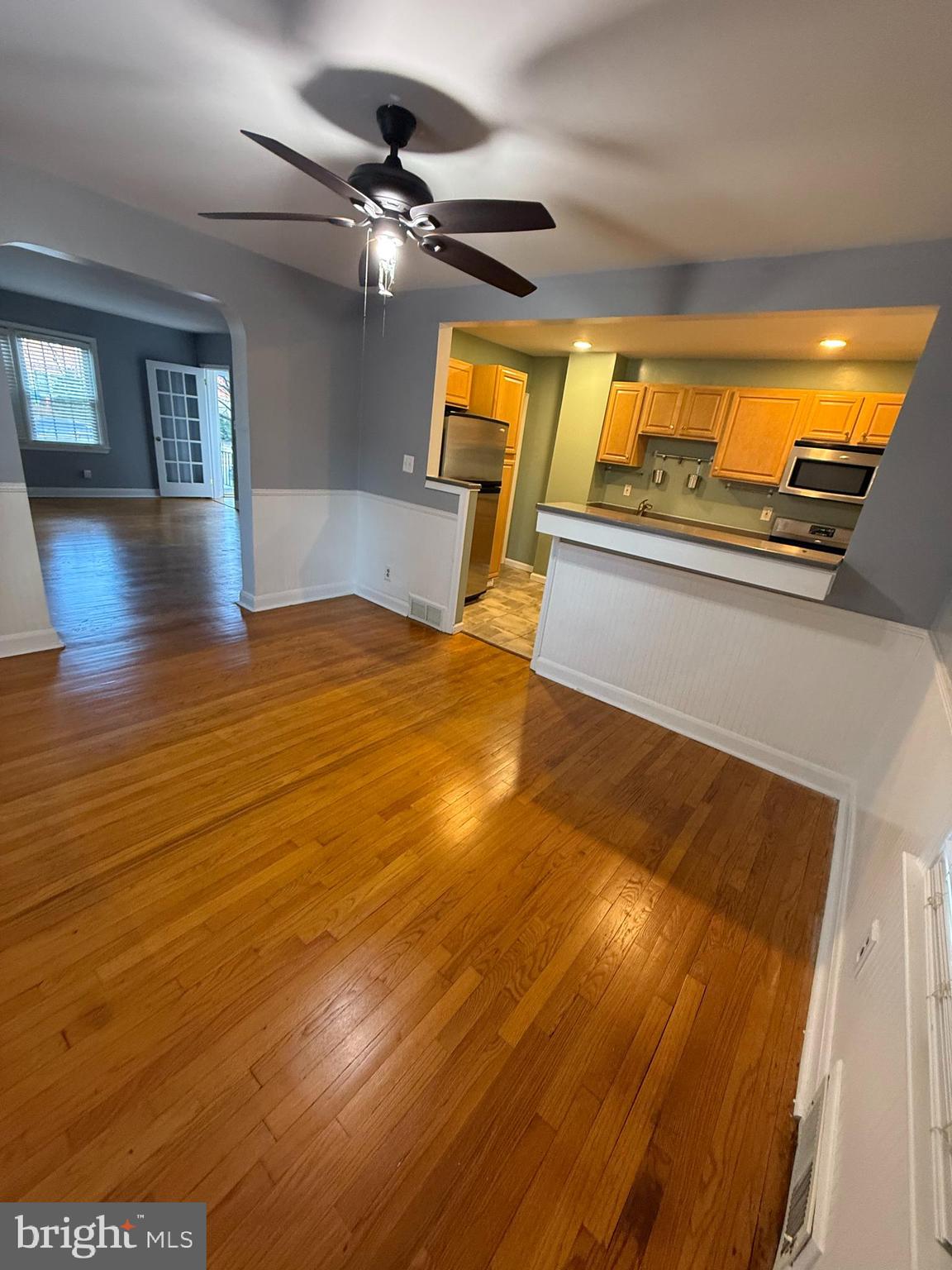 a view of an empty room with wooden floor and windows