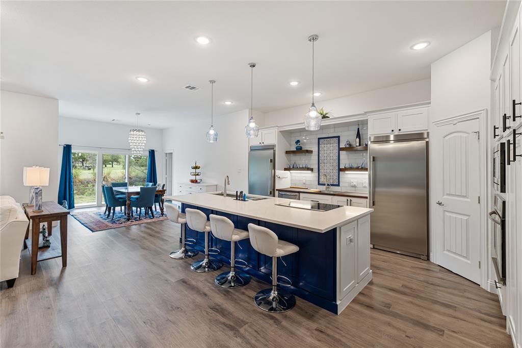 a kitchen with stainless steel appliances granite countertop a table chairs wooden floors and a view of living room