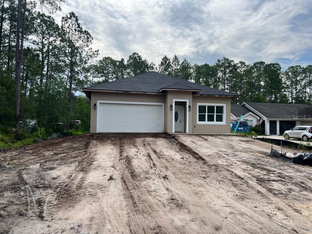 a view of house with backyard and trees in the background