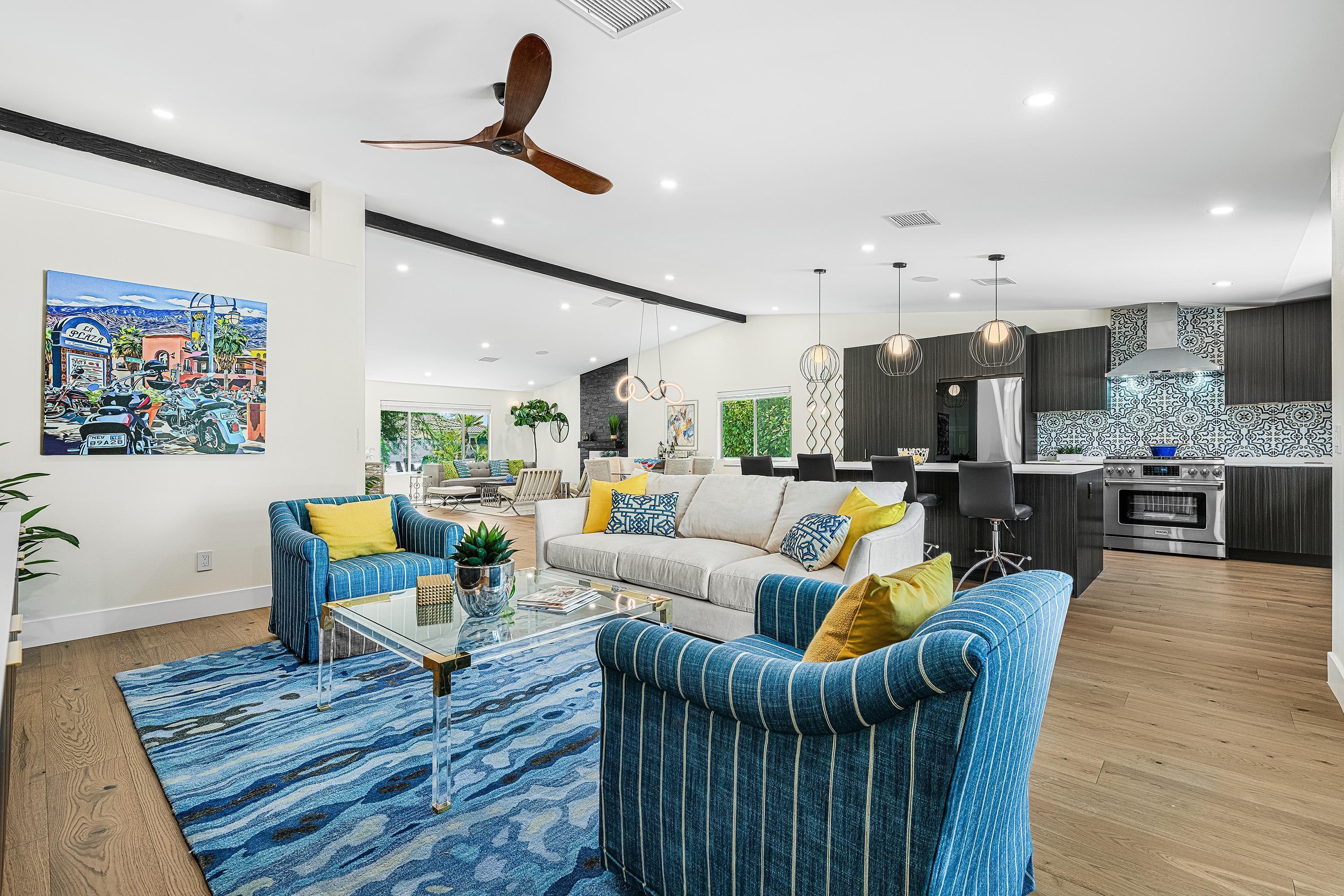 a living room with furniture kitchen view and a wooden floor