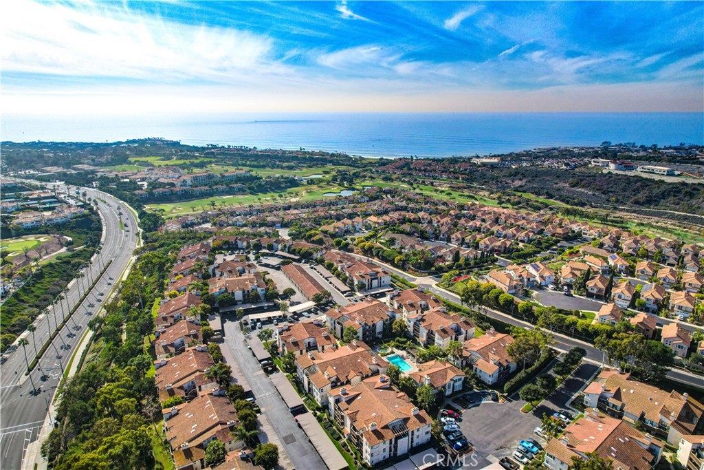 an aerial view of a city with lots of residential buildings ocean and mountain view in back