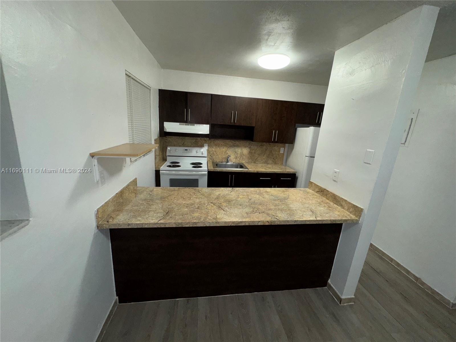 a room with kitchen island stainless steel appliances a sink stove and refrigerator