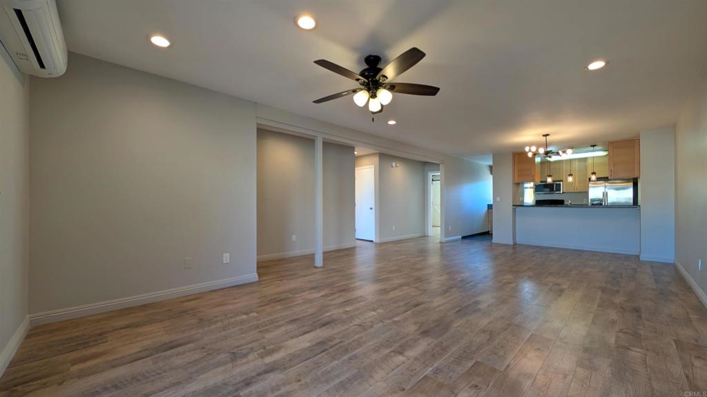 a view of an empty room with kitchen and a window