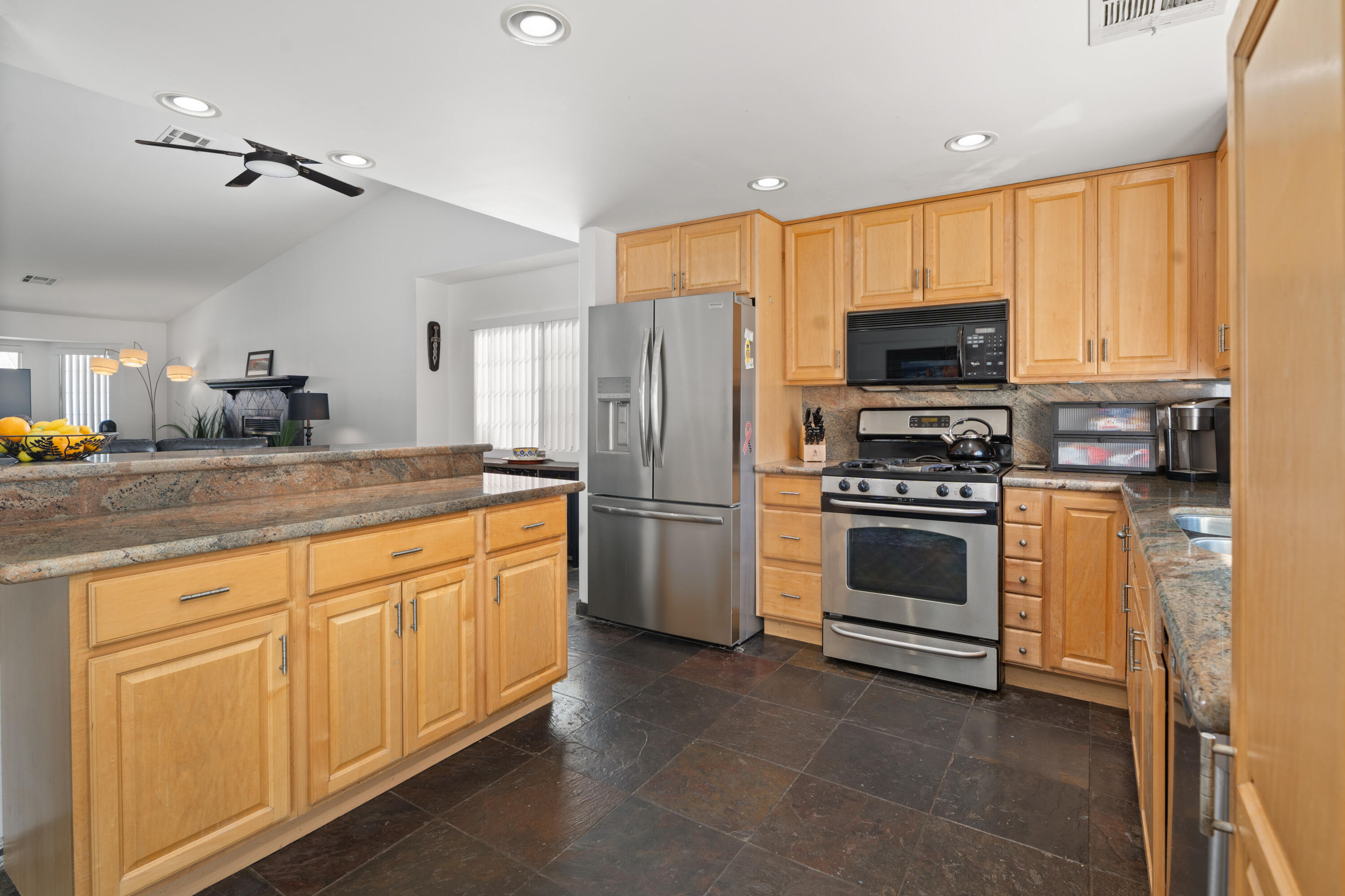 a kitchen with granite countertop a refrigerator stove and microwave