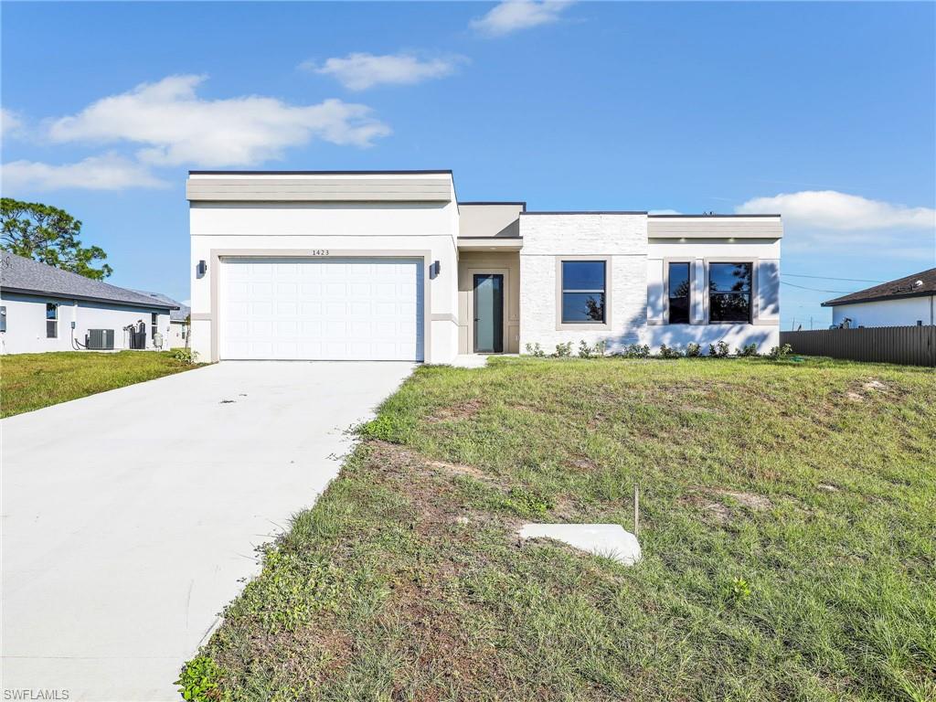 View of front of property featuring cooling unit, a front yard, and a garage