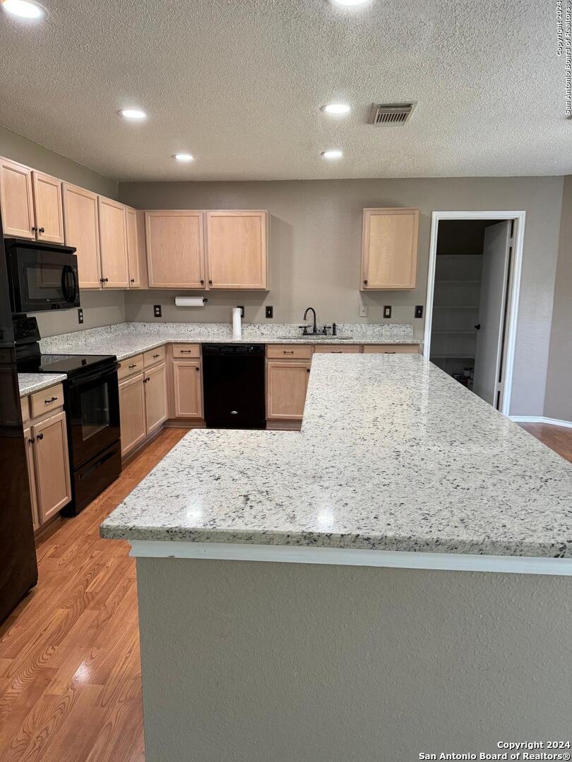 a large kitchen with kitchen island granite countertop a sink counter space and stainless steel appliances