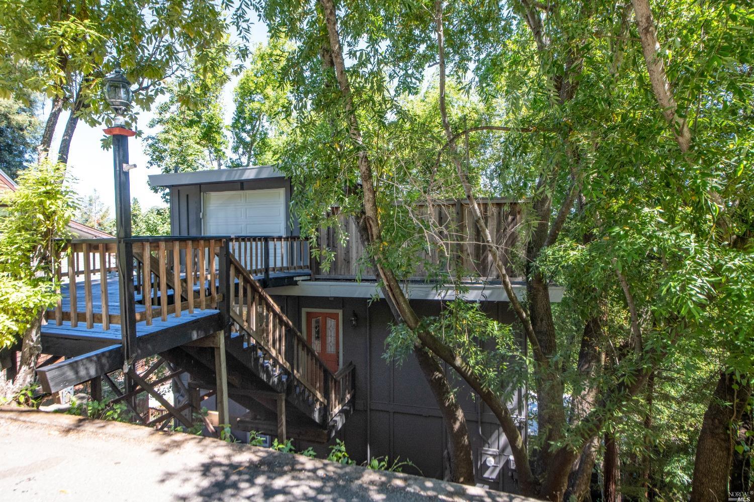 a house view with a wooden deck and a trees