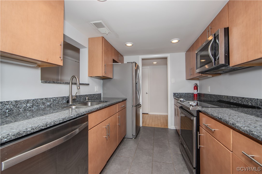 a kitchen with stainless steel appliances granite countertop a sink and a refrigerator