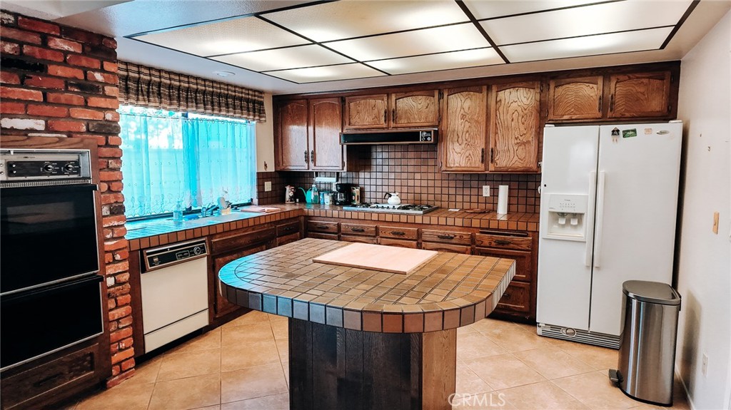 a kitchen with stainless steel appliances granite countertop a refrigerator a sink and a stove