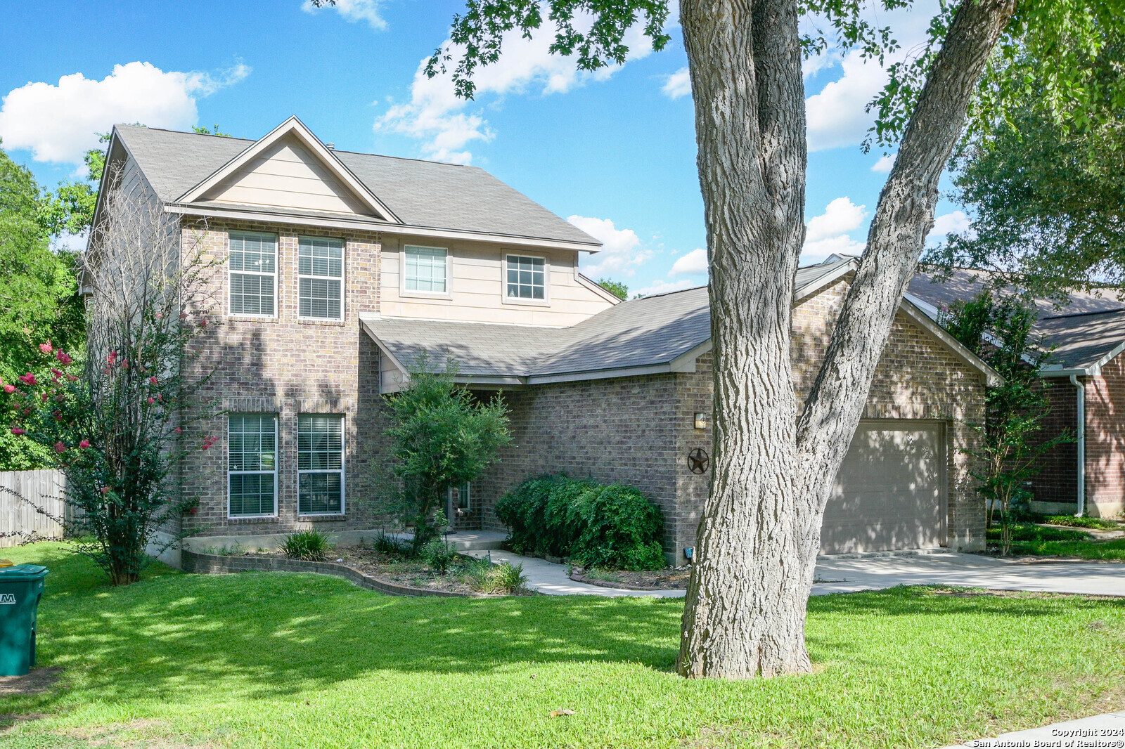 a front view of a house with a garden and a tree