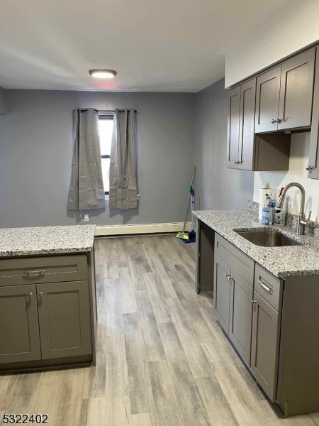 a kitchen with granite countertop a sink cabinets and wooden floor