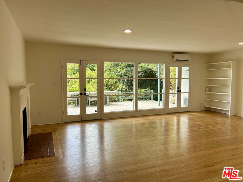 a view of an empty room with a window and wooden floor